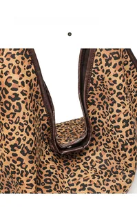 Close-up of leopard print tote bag fabric with magnetic closure and leather trim detail