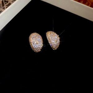 Macro detail of crescent moon stud earrings with pavé crystals on a black background