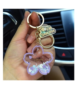 Macro view of cherry blossom liquid keychain with floating purple sequins and acrylic charms