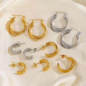 Chic gold and silver stainless steel C-shaped hoop earring set on beige silk background