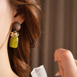 Macro shot of geometric earrings featuring dark wood discs and green resin pendants