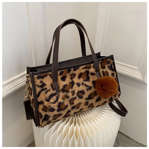 Detail of leopard print faux fur tote bag with plush pompom and brown leather handle