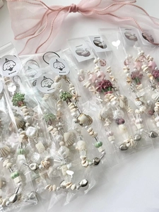 Close-up of handmade beaded summer phone charms with shells and stars in individual packaging