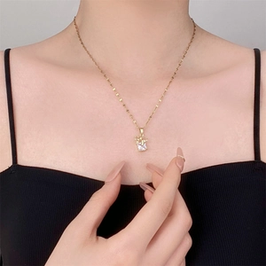 Collier élégant avec pendentif nœud et zircon en acier titane doré porté par un mannequin