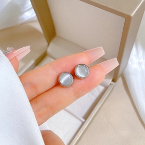 Close-up of titanium steel earrings with round cat eye stones held in hand