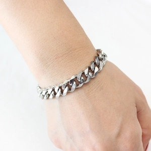 Macro shot of silver stainless steel NK flat Cuban link chain bracelet on wrist