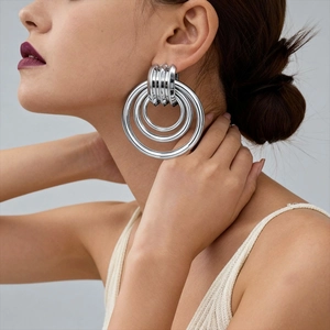 Macro side view of silver multi-layered geometric circular drop earrings on a model