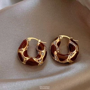 Detailed macro view of gold-plated hoop earrings with red enamel and sparkling zircons
