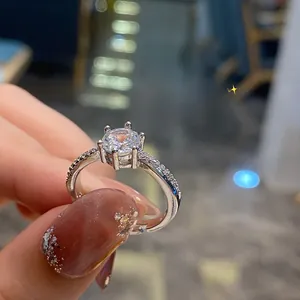 Detailed view of silver six-prong round diamond ring held in hand for scale and brilliance