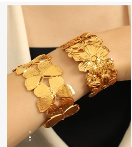 Detail of 18K gold plated wide cuff bangle featuring 3D butterfly and floral reliefs