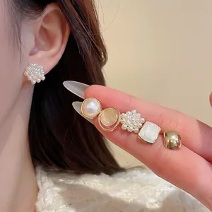 Elegant gold earrings set with pearls and zircons shown on hand for daily wear