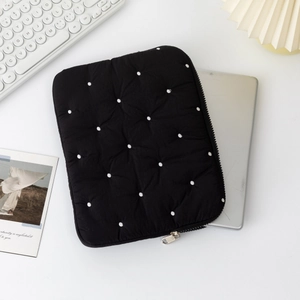 Detailed view of black quilted laptop sleeve with white polka dots and silver tablet inside