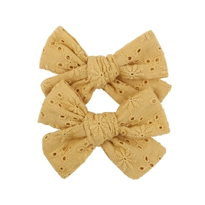 Detail of yellow cotton lace bow hair clips with delicate floral embroidery for girls