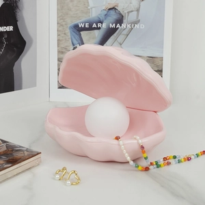 Pink ceramic shell night light with round bulb used as jewelry storage tray