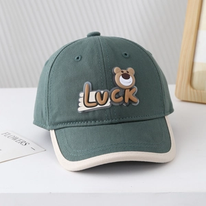 Détail de la casquette baseball en coton vert foncé avec écusson ours Luck et bord crème