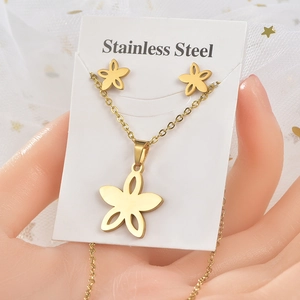 Macro view of gold stainless steel hollow five-petal flower necklace and stud earrings set