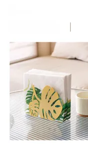 Detail of gold metal napkin holder featuring a minimalist tropical monstera leaf design