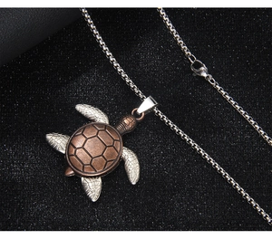 Detail view of retro turtle pendant with bronze shell and silver limbs on black texture