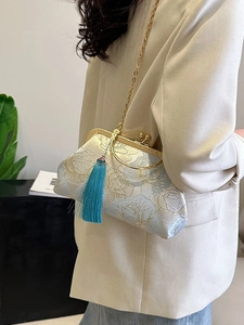 Light blue floral embroidery shell bag with long tassel and gold chain strap worn by model