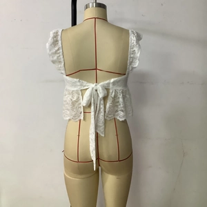 Detailed back view of white lace camisole featuring hollow floral patterns and a bow tie back