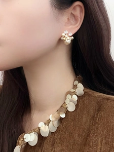 Gros plan de boucles d'oreilles fleurs plaquées or 18k avec perles et cristaux sur modèle