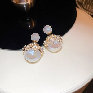 Detail of elegant gold-plated crown earrings with iridescent pearls and diamonds