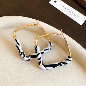 Chic gold square hoop earrings with zebra print leather wrap on beige tray