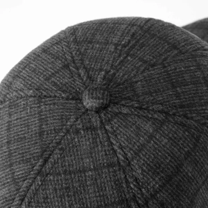 Close-up of a charcoal grey corduroy baseball cap top button and vertical texture detail