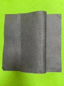 Close-up of thick grey microfiber magic cleaning cloths stacked on a green surface