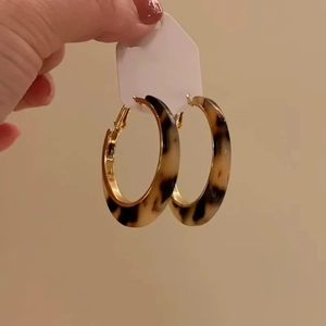 Detailed view of leopard print resin hoop earrings with elegant gold metal accents