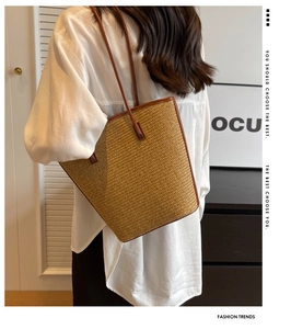 Detail shot of a striped woven straw tote bag with brown leather trim and shoulder straps