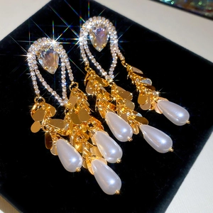 Detail of luxury gold teardrop pearl earrings with sparkling white rhinestones