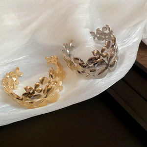 Détail de bracelets feuilles dorés et argentés avec nervures sur tissu blanc