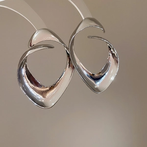 Vista macro di orecchini geometrici in argento con finitura in metallo liquido lucido e design