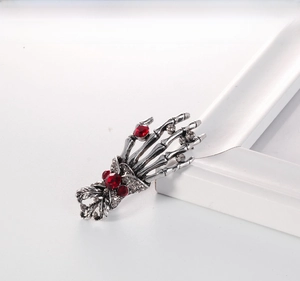 Close-up of gothic skeleton hand brooch with red rhinestones and antique silver finish