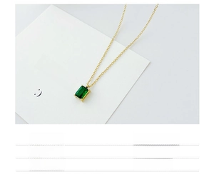 Detalle de un collar de titanio chapado en oro con un colgante de gema verde corte esmeralda