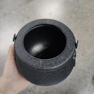 Close-up of black plastic witch cauldron candy bucket with matte texture and handles