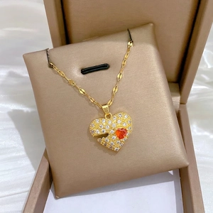Golden heart necklace with white crystals and small red gemstone on champagne silk