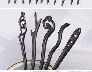 Close-up of hand-carved ebony wood hair pins in a ceramic bowl with silk fabric