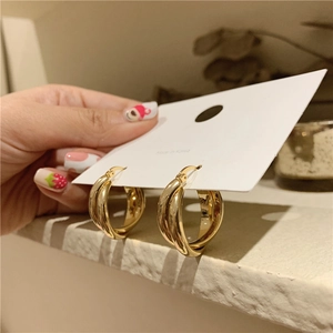 Golden double hoop twisted earrings shown on a model in a warm home setting detail