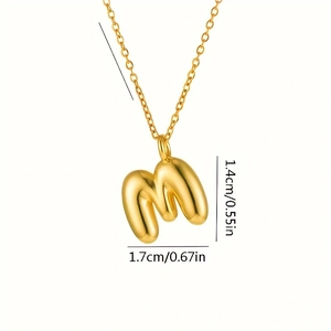 Vista macro del pendente lettera M 3D dorata con dimensioni 1,4 cm per 1,7 cm per collana