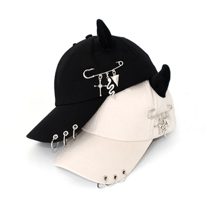 Close-up of hip-hop baseball cap with devil horns, metal rings, and cross pin pendants