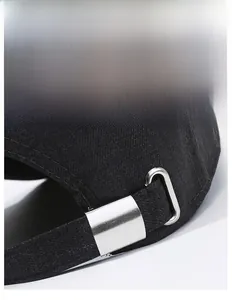 Detail of adjustable metal buckle and cotton fabric texture on back of black baseball cap