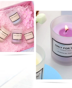 Macro view of a lit soy wax candle in a frosted glass jar with elegant gift box packaging