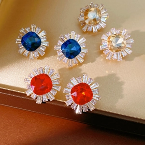 Detailed shot of square-cut zircon stud earrings in red, blue and champagne colors
