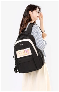 Detail of high-capacity nylon backpack featuring transparent PVC window and plush charm