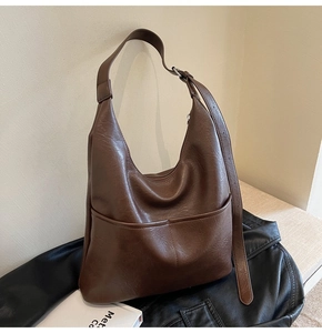 Detail of dark brown faux leather hobo bag with visible stitching and adjustable strap