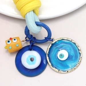 Détail de breloque œil bleu avec perle baril jaune et cordon tressé pour porte-clés