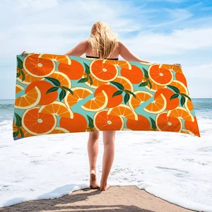Detail showing the microfiber beach towel with orange fruit prints and blue sky background