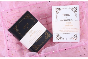 Close-up of black and white mini bilingual book of answers in pink gift basket